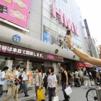 For the memory: A woman takes pictures of HMV flagship outlet in Tokyo\'s trendy Shibuya area on Sunday with her cell phone. The flagship music store closed for good later in the day. | KYODO PHOTO