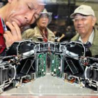 Internal workings: Visitors look at a cross section of a Pentax 645D body and lens at the Camera and Photo Imaging Show in Yokohama in March. Some shareholders are calling for executive pay at Pentax parent Hoya Corp. to be disclosed. | BLOOMBERG PHOTO
