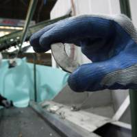 Second life: A rare earth magnet, recovered from a discarded hard drive, is picked up at Hitachi Plant Technologies Ltd.\'s research laboratory in Matsudo, Chiba Prefecture, on Monday. | BLOOMBERG PHOTO