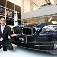 Booming business: Jun Kubota, sales manager for BMW Aoyama Square, poses next to a 523i at the company\'s showroom in Tokyo on May 30. | BLOOMBERG PHOTO