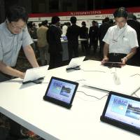 Checking things out: DoCoMo\'s Galaxy tablet device, manufactured by Samsung Electronics Co.,  is examined by members of the media in Tokyo in early September. | BLOOMBERG