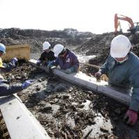 Clearing the way: Workers sort debris in Minamisanriku, Miyagi Prefecture, on March 1, nearly a year after the resort town was devastated by tsunami. | AP