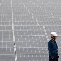 Bright hopes: A worker checks panels at the Ogishima solar power plant in Kawasaki, run by local authorities and Tokyo Electric Power Co., in December. | BLOOMBERG