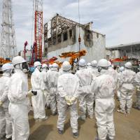 Hot spot: Reporters and Tokyo Electric Power staff view the blown-out building for reactor 4 at Tepco\'s Fukushima No. 1 power plant near Okuma, Fukushima Prefecture, on May 26. | BLOOMBERG