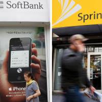 Acquisition target: A woman walks by a SoftBank shop in  Tokyo on April 26 while a man walks past a Sprint store (right) in 2010 in New  York. | AP