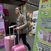 Cashing out: A tourist walks past a currency exchange store in Seoul\'s Myeongdong shopping district in October. | BLOOMBERG