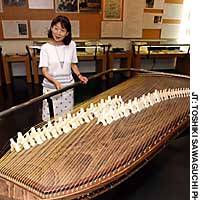 Shizue Makise, administrative manager of Michio Miyagi Memorial Hall and a distant relative of the musician, displays a reproduction of the koto Miyagi invented. | PHOTO COURTESY OF THE NATIONAL ASTRONOMICAL OBSERVATORY OF JAPAN