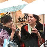 Two women in traditional kimono brave the snow at Hamarikyu Park in Tokyo\'s Minato Ward on Friday for free sake served in bamboo cups. The sake was part of a New Year\'s event that included a demonstration of falconry and the tea ceremony. | PHOTO COURTESY OF DEFENSE AGENCY