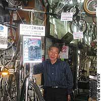 Kesashichiro Tagawa, owner of a bicycle shop in Osaka\'s Hirano Ward, stands beside a bike recognized in the 1994 Guinness Book of Records as the biggest in the world. The shop doubles as the Bicycle Museum. | PHOTO COURTESY OF OMIYA LAW SCHOOL