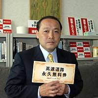 Yasuyo Yamazaki holds up a mock \"toll-free\" expressway ticket at his office in Tokyo. | TETSUSHI KAJIMOTO PHOTO
