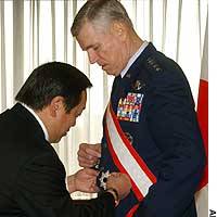 Gen. Richard Myers, chairman of the U.S. Joint Chiefs of Staff, receives a decoration from Vice Defense Minister Yasukazu Hamada at the Defense Agency in Tokyo. | KYODO ILLUSTRATION