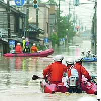 Firefighters travel by boat to rescue people who have been left stranded by floods brought about by heavy rain in Sanjo, Niigata Prefecture. | HIROSHI MATSUBARA PHOTO