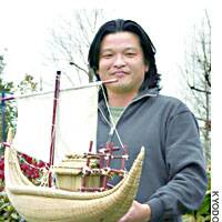 Adventurer Jin Ishikawa holds a miniature of a reed boat he plans to use for a 1,000-km voyage in May between Cape Ashizuri in Kochi Prefecture and the Izu Islands. | KYODO PHOTO