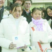 Myanmarese Soesoemin and her daughter, Minsoeseet, show off special permits that allow them to stay in Japan. | PHOTO COURTESY OF THE JAPAN FOUNDATION/KYODO