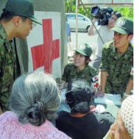 Self-Defense Forces personnel take notes at their clinic in Bantul, Indonesia, on Saturday as residents hit by the deadly May 27 earthquake explain their medical needs. | JAPAN AEROSPACE EXPLORATION AGENCY PHOTO/KYODO