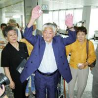 Yoshiteru Nakagawa (center) shouts \"Banzai\" at New Chitose Airport in Hokkaido before departing for Russia on Sunday morning. | KYODO PHOTO