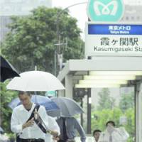 Commuters emerge from Kasumigaseki Station in Tokyo amid a downpour as Typhoon Maria approached the Kanto region Wednesday. | KYODO PHOTO