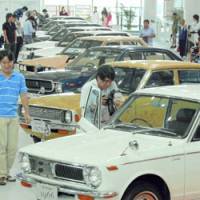 Visitors view past Toyota Corolla models Tuesday at an exhibition in Tokyo\'s Odaiba district. | KYODO PHOTO