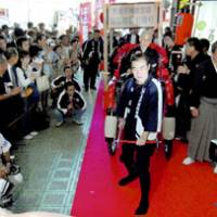 Katsura Sanshi, head of a \"rakugo\" storytellers association, pulls prominent rakugo performer Katsura Harudanji III in a jinrikisha Friday morning to mark the opening of the Temma Tenjin Hanjo Tei theater in Osaka. | KYODO PHOTO