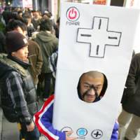 Kentaro Watanabe, wearing a papier-mache Wii controller, waits for Nintendo Co.\'s new video game console to go on sale at the Bic Camera in Tokyo\'s Yurakucho district Saturday. | AP PHOTO