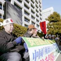 Plaintiffs gather Monday outside the Health, Welfare and Labor Ministry to demand that the government not appeal a court ruling that held it liable for failing to take adequate steps to resettle them from China after the war. | KYODO PHOTO