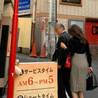 A couple discreetly enter a love hotel in Tokyo\'s Dogenzaka district. | YOSHIAKI MIURA PHOTOS