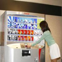 Cashless purchase: A woman uses a cell phone with an electronic-money function to buy a beverage from a vending machine. | COURTESY OF COCA-COLA (JAPAN) CO.