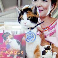 On duty: Tama the \"stationmaster\" cat poses with a photo book featuring herself at Kishi Station on the Kishigawa Line in Wakayama Prefecture in September. | KYODO PHOTO