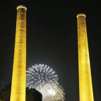Centennial: Fireworks burst in the night sky over Tagawa, Fukuoka Prefecture, during a festival Saturday commemorating these two 100-year-old chimneys. | KYODO PHOTO