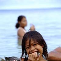 Island girl: Fatogea Matagale eats fresh fish just caught in the sea of Funafuti Island in April 2007. She told photographer Shuichi Endo, \"I am happy whenever I play a kick-the-can game with my friends. I wish to make more friends.\" | COURTESY OF SHUUICHI ENDOU