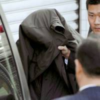 Suspect: Police put Dang Xuan Hop into a car at Fukuoka airport Wednesday. | KYODO PHOTO