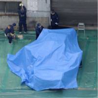 CSI Osaka: Crime scene investigators search a taxi covered with a large tarp Tuesday after its driver was found slain in a factory parking lot in the city of Higashiosaka, Osaka Prefecture. | KYODO PHOTO