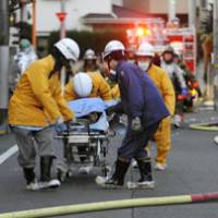 Deadly blaze: Rescue team members carry a victim from a fire that killed four people Wednesday in Setagaya Ward, Tokyo. | KYODO PHOTO