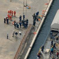 The plank: Workers gather near an iron gangway that collapsed at a shipyard in the city of Oita on Friday. | KYODO PHOTO