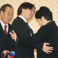 Poignant embrace: Koichiro Iizuka, the son of abductee Yaeko Taguchi, meets former North Korean agent Kim Hyon Hui on Wednesday in Busan, South Korea, as Taguchi\'s brother, Shigeo Iizuka, looks on. | KYODO PHOTO
