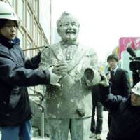 Resurrected: A construction worker supports a statue of Kentucky Fried Chicken founder Colonel Sanders on Wednesday after reassembling it with parts discovered in Osaka\'s Dotonbori River the previous day. | KYODO PHOTO