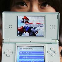 Milestone: A model shows a Nintendo DS Lite during a news conference in Tokyo in 2006. | AP PHOTO