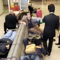 Holding pattern: Stranded travelers lie on benches early Tuesday in a passenger terminal at Narita International Airport after a FedEx cargo plane crash the previous day disrupted flights. | KYODO PHOTO