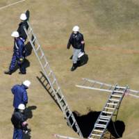 Hidden danger: Police investigate a sinkhole on a fairway at Le Petaw golf course in Hokkaido on Friday after a woman suddenly disappeared into it and drowned during play. | KYODO PHOTO