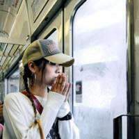 In remembrance: A woman offers a moment of silence inside a JR Fukuchiyama Line train as it passes the site of the deadly 2005 derailment that killed 107 people in Amagasaki, Hyogo Prefecture, on Saturday. | KYODO PHOTO