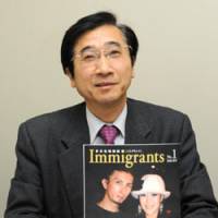 Spread the word: Immigrants magazine editor in chief Susumu Ishihara holds up a copy of the first edition in Minato Ward, Tokyo, on April 7. Ishihara is also president of the Japan Immigrant Information Agency. | SATOKO KAWSAKI PHOTO