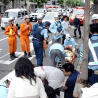 First responders: Rescue workers treat people hit by a car while walking on a sidewalk Sunday in Shimogyo Ward, Kyoto. | KYODO PHOTO