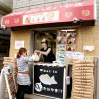 Pancake monger: An Onagaya \"taiyaki\" stall in the Kamata district of Ota Ward, Tokyo, serves a customer Friday. | YOSHIAKI MIURA PHOTO