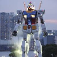 Bow down: An 18-meter tall Gundam statue towers over admirers at a Tokyo park on July 11. The full-size model of Japan\'s popular animated robot character was erected to mark the 30th anniversary of the start of the TV series \"Mobile Suit Gundam.\" | AP PHOTO