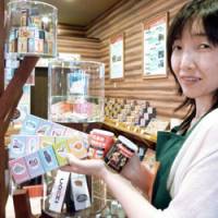 In all shapes and sizes: A clerk shows match products on sale at Match-bo in Kobe, including moisture-proof canned matches for emergency use in this recent photo. | KYODO PHOTO