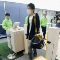 Stepped-up security: A man passes through a new explosives detector developed by Hitachi during a test Tuesday at Tokyo\'s Haneda airport. | KYODO PHOTO
