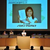 Picture this: Nomiun Delgerkh, 18, presents her favorite Japanese word, \"mieruka,\" at an event on Tuesday at Nikkei Hall in Chiyoda Ward, Tokyo. The Mongolia teen and 13 other young foreigners participated in a cultural experience program run by NPO Japan Return Program this summer. | YOSHIAKI MIURA PHOTOS