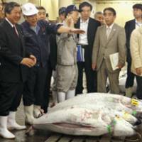Making the rounds: Farm minister Hirotaka Akamatsu (left) listens to an official at the Tsukiji fish market in Tokyo on Thursday. | KYODO PHOTO