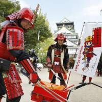 Heisei Restoration?: Members of a nonprofit organization wear samurai armor while picking up garbage in front of Osaka Castle. | KYODO PHOTO
