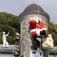 Special delivery: A huge Santa Claus doll wearing a surgical mask is installed on the exterior of Uroko no Ie (House of Scales) Monday in Kobe\'s Kitano district. | KYODO PHOTO